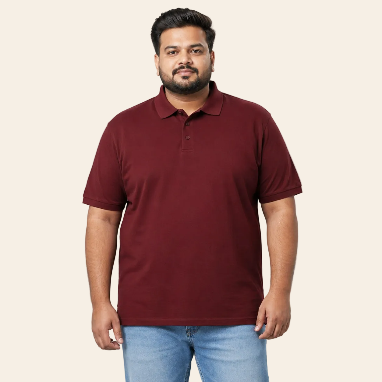 Man wearing a maroon polo shirt and blue jeans on a gray background